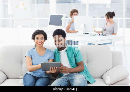 Couple using digital tablet with colleagues at creative office Stock Photo