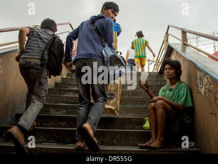 Pasay City, Philippines-January 20, 2014: A homeless asking for some money in the Pasay Rotunda overpass. Stock Photo