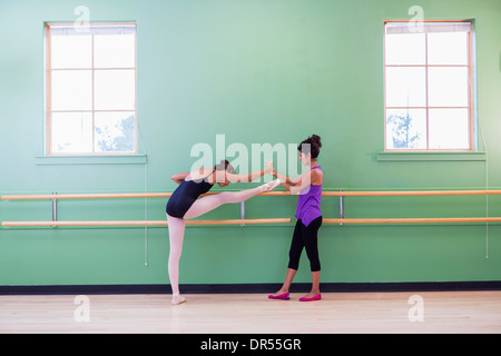 Mixed race ballerina practicing with teacher at barre Stock Photo
