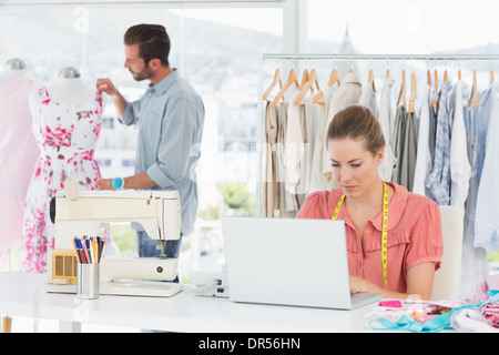 Woman using laptop with fashion designer working at studio Stock Photo