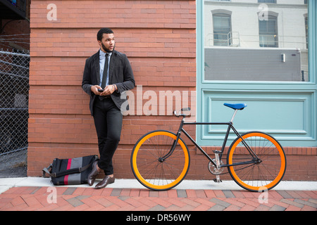 Mixed race businessman with bicycle on urban sidewalk Stock Photo