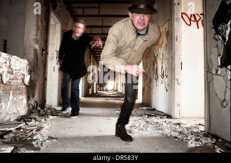 Man runs away from his chaser in an abandoned building Stock Photo