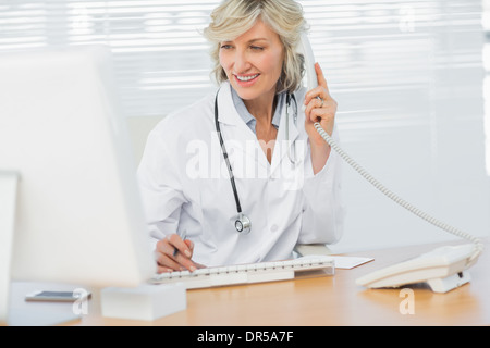 Doctor with computer using phone at medical office Stock Photo
