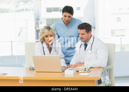 Three concentrated doctors using laptop together Stock Photo