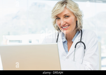 Smiling female doctor using laptop in medical office Stock Photo