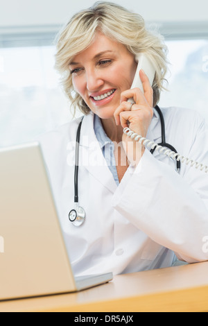 Female doctor using laptop and phone in medical office Stock Photo