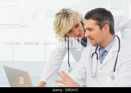 Two concentrated doctors using laptop together Stock Photo