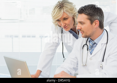 Two concentrated doctors using laptop together Stock Photo