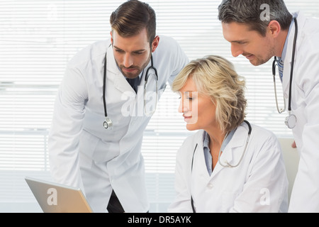 Three concentrated doctors using laptop together Stock Photo