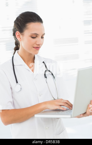 Concentrated young female doctor using laptop Stock Photo
