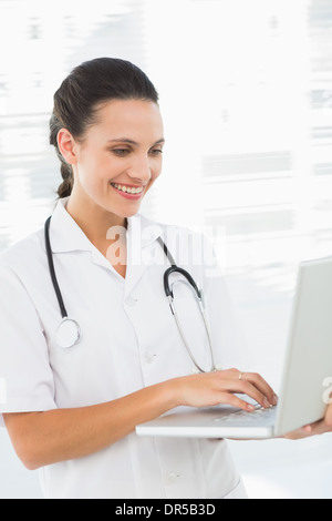 Concentrated smiling female doctor using laptop Stock Photo