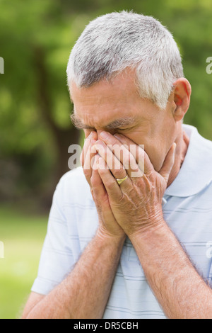 Senior man with head in hands at park Stock Photo