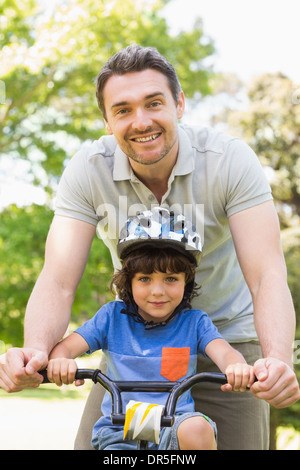 Man teaching his son to ride a bicycle Stock Photo
