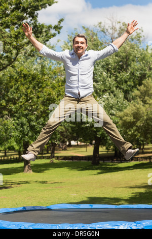 Happy man jumping high on trampoline in park Stock Photo