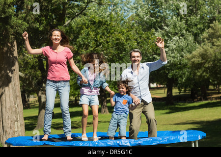 Happy family jumping high on trampoline in park Stock Photo