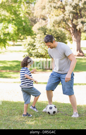 Father and son playing football in the park Stock Photo