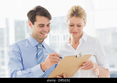 Smiling business team looking at clipboard together Stock Photo