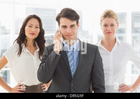 Smiling businessman on the phone in front of his team Stock Photo