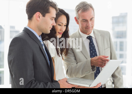 Business team looking at laptop together Stock Photo