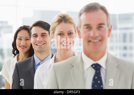 Cheerful business team standing in a line smiling at camera Stock Photo