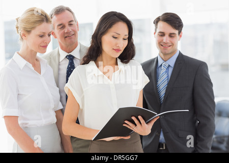 Businesswoman reading a document with her team Stock Photo