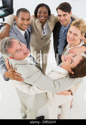 Diverse business team hugging in a circle smiling at camera Stock Photo