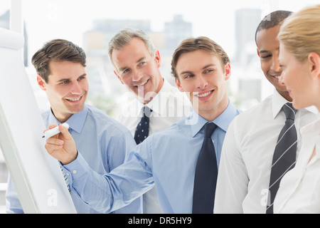 Young businessman writing on whiteboard with colleagues Stock Photo