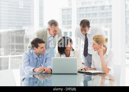Business people gathered around laptop discussing Stock Photo