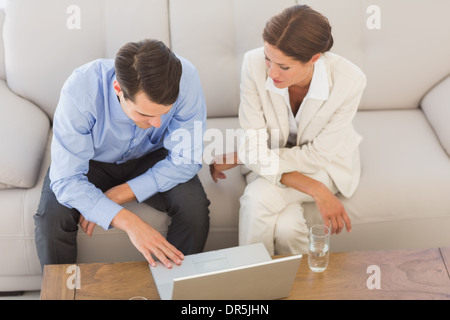 Business partners working together on laptop sitting on sofa Stock Photo