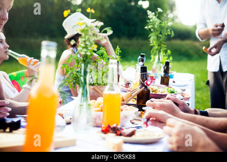 Friends barbecuing on the riverside, picnic table in foreground, Bavaria, Germany Stock Photo