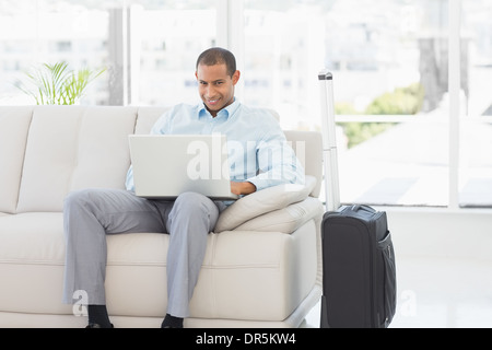 Happy businessman using laptop waiting to depart on business trip Stock Photo