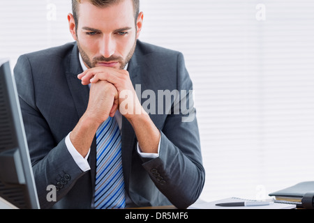 Thoughtful businessman sitting at office desk Stock Photo
