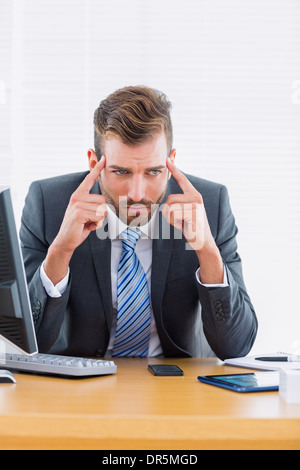 Businessman with severe headache at office desk Stock Photo