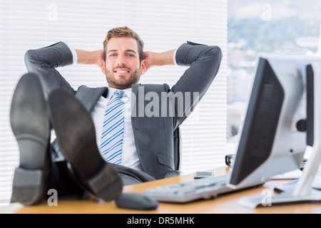 Relaxed businessman sitting with legs on desk Stock Photo