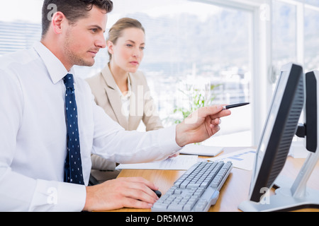 Smartly dressed colleagues using computer Stock Photo