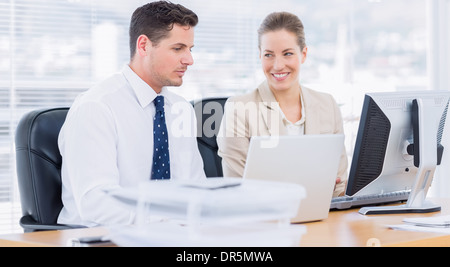 Smartly dressed colleagues using computer Stock Photo