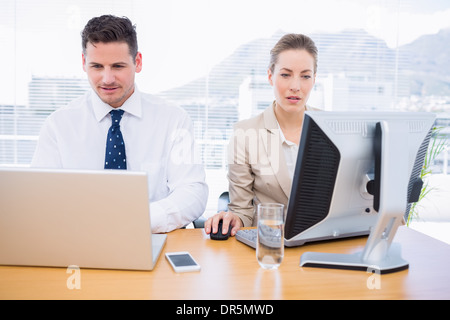 Smartly dressed colleagues using computer and laptop Stock Photo