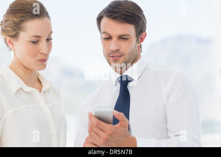 Smartly dressed colleagues looking at mobile phone Stock Photo