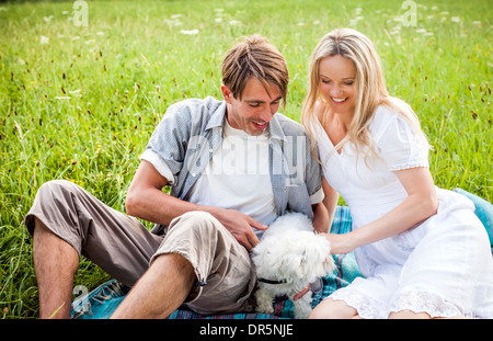 Happy couple with dog relaxes in the meadow, foothills of the Alps, Bavaria, Germany Stock Photo