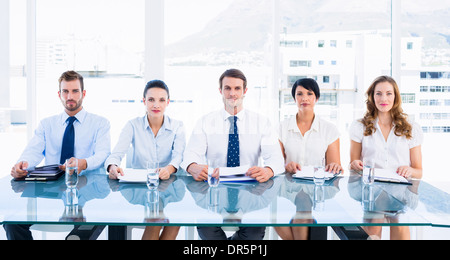 Smartly dressed executives sitting in row at desk Stock Photo