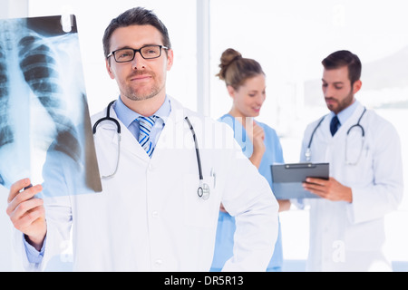 Male doctor examining x-ray with colleagues behind Stock Photo