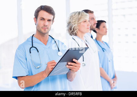 Portrait of a male doctor writing reports with colleagues behind