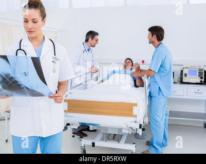 Doctor examining x-ray with colleagues and patient in hospital Stock Photo