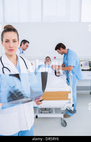 Doctor holding x-ray with colleagues and patient in hospital Stock Photo