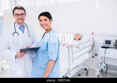 Doctors discussing reports with patient in hospital Stock Photo