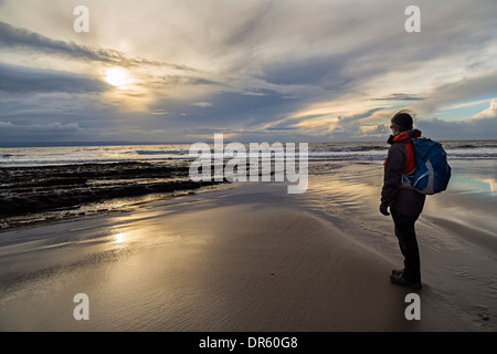 Woman hiker standing on beach, at sunset, Dunraven, Glamorgan, Wales, UK Stock Photo