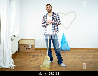 Man standing with broom against heart shape on wall, Munich, Bavaria, Germany Stock Photo