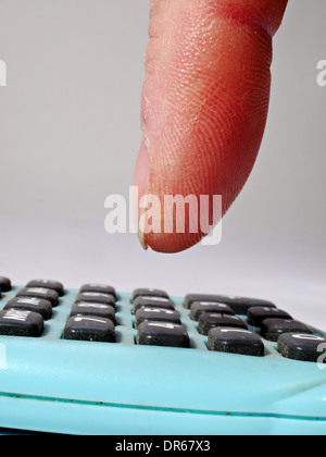 A finger is about to push a button on a small calculator Stock Photo