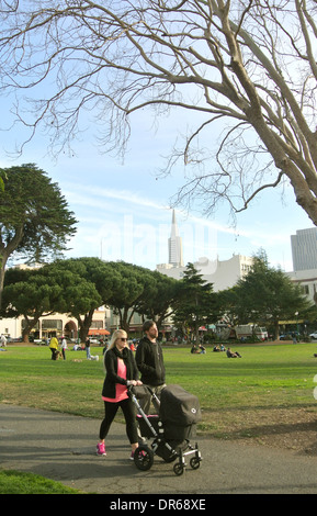 couple with baby stroller walk in washington Square Park in San Francisco Stock Photo