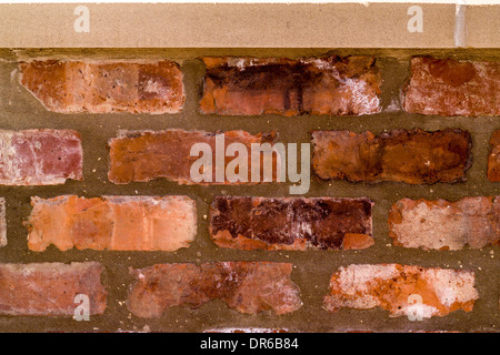 Brick wall constructed with reclaimed bricks, with sandstone coping stone on top Stock Photo